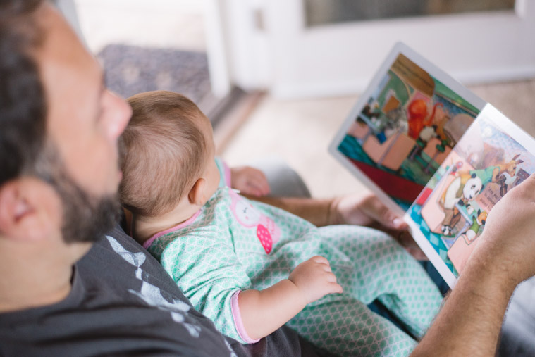 A father and his infant daughter look at a book together