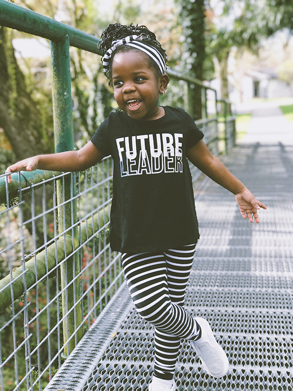 A young girl stands on a bridge wearing a shirt that says Future Leader highighting Ready Ready's committment to the future.